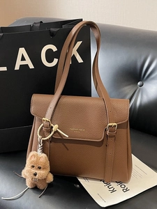 Brown lychee leather tote bag with a plush dog pendant and stylish shoulder strap