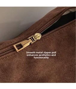 Detailed close-up of premium gold-tone metal zipper on a dark brown suede tote bag