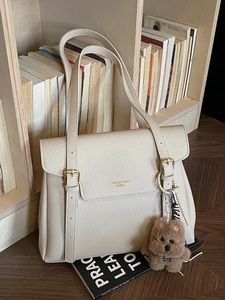 Minimalist cream tote bag with litchi pattern and plush bear charm on wooden shelf