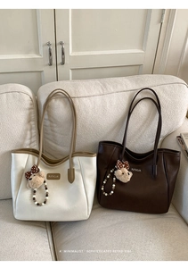 Détail de grands sacs cabas avec logo de la marque et pendentif ours sur un canapé