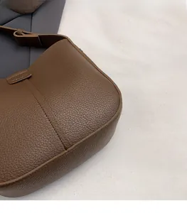 Detail showing dark brown lychee grain leather texture and side stitching on the handbag