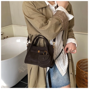 Detail of dark brown suede bucket bag with gold ring hardware and mini pouch accessory