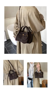 Detail of dark coffee suede bucket bag with gold hardware and mini charm pouch