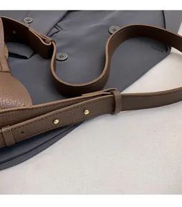 Detail of dark brown lychee leather strap with golden metal buckles on a blazer