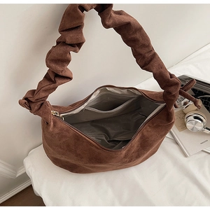 Detail of brown faux suede tote bag featuring a pleated handle and interior zipper pocket