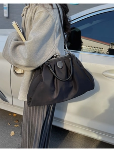 Detail of a black pleated tote bag with a metal doctor bag frame for large storage