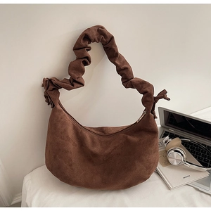 Detail of coffee suede crescent tote with pleated shoulder strap and side ribbon bow