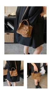 Close-up of brown suede bucket bag featuring golden buckle and a matching round coin purse