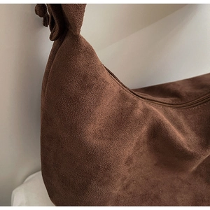 Detailed view of dark brown suede crescent bag with knotted shoulder strap and zipper