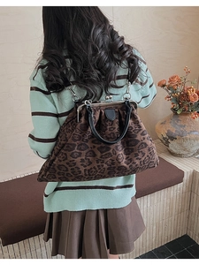Close-up of vintage leopard print doctor bag with metal clasp and black leather handle