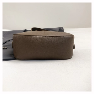 Detail view of the pebbled leather oval bottom of this coffee brown crossbody bag