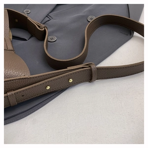 Close-up of brown litchi leather strap with gold studs on a grey suit background