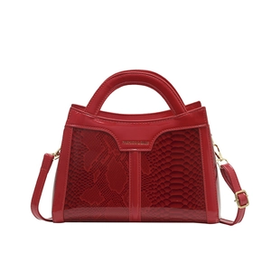 Elegant bright red patent leather handbag with snakeskin texture and golden strap hardware