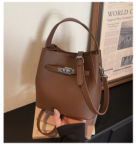 Detail of dark brown lychee leather bucket bag with metallic twist lock and handle
