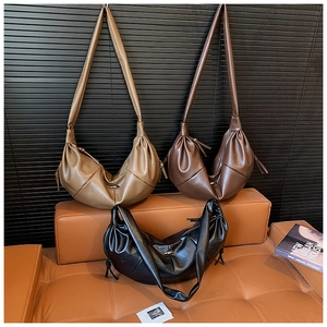 Detailed shot of three crescent shoulder bags in khaki, brown, and black PU leather