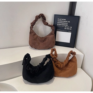 Three suede crescent shoulder bags in brown, black and tan with ruched handles on a stand