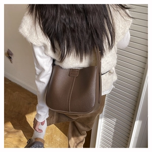 Detail of dark brown lychee leather texture and wide strap on minimalist crossbody bag