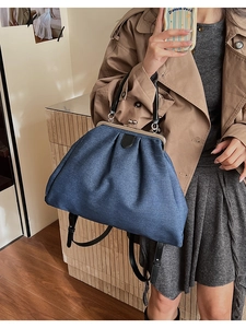 Detail of blue denim tote bag featuring vintage metal kiss-lock closure and leather strap