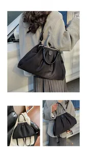 Detail of black pleated tote bag showing fabric texture and elegant metal clasp design