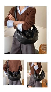 Detail of a minimalist black pleated hobo bag with zip closure and smooth finish