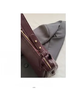 Dettaglio dell'hardware dorato e pelle testurizzata su una borsa sottobraccio bordeaux