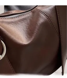 Close-up of brown leather handbag texture with silver zipper and precise stitching details