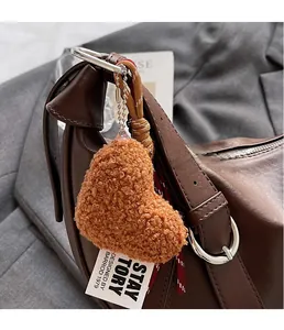Close-up of a brown heart-shaped plush keychain on a premium leather shoulder bag