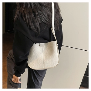 Detailed view of white lychee grain leather crossbody bag with a semi-circular design