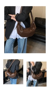Detail of dark brown leather crescent bag with elegant pleated texture and wide strap