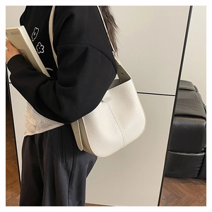Close-up of cream pebble grain leather texture and minimalist buckle on shoulder bag
