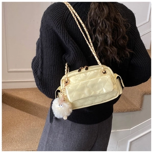 Vue détaillée du sac matelassé jaune pâle à chaîne avec un pendentif pompon doux