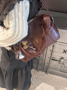 Retro brown leather Boston bag with heart pendant and leopard bow on industrial background