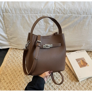 Detail of dark brown pebble leather bucket bag with silver turn-lock and fine stitching