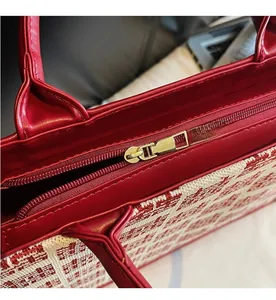 Détail de la fermeture éclair dorée sur un sac à main de mariée rouge en tissu tissé