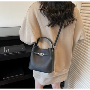 Black lychee leather bucket bag featuring a silver metal turn-lock and leather strap
