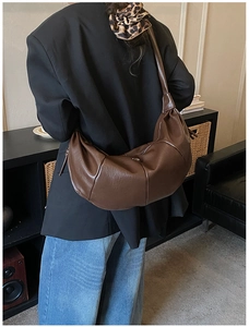 Detail of dark brown vintage crescent bag showing leather texture and ruched strap design