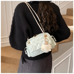 Detalle del bolso acolchado verde menta con cadena dorada y pompón blanco en modelo