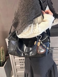 Retro black leather Boston bag with leopard heart charm worn as a stylish crossbody bag