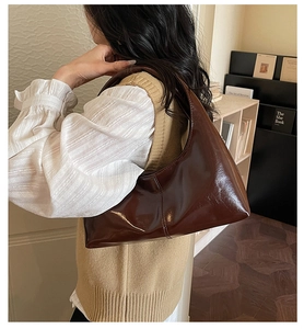 Detail of dark brown glossy patent leather shoulder bag with vertical stitching
