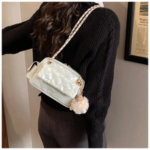 Gros plan sur le sac chaîne en cuir matelassé vert menthe avec un pendentif mouton en peluche