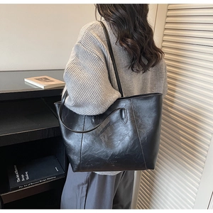 Detail view of high-capacity black tote bag with natural grain texture and leather shoulder strap