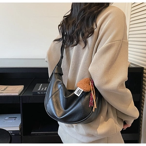 Detail of black hobo bag with leather texture and heart plush charm for daily commute