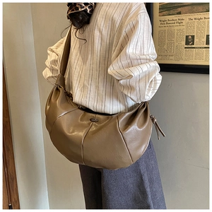 Detail of the oversized dark beige crescent hobo bag with wide strap and metallic logo