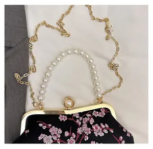 Close-up of vintage floral embroidery and elegant pearl handle on black evening bag