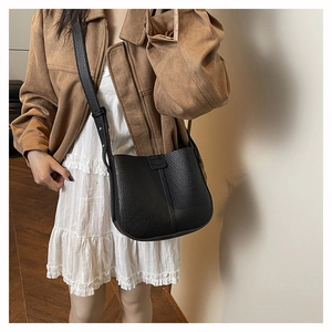 Detail of black lychee grain leather bucket bag featuring a minimalist vertical center seam