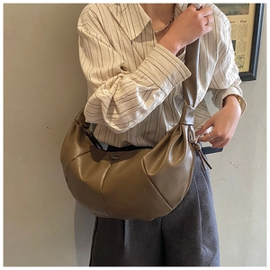Model wearing a brown pleated half-moon bag with elegant vintage leather textures