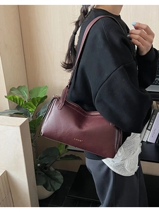 Dettaglio borsa Boston in pelle bordeaux con logo LULU dorato e cerniera metallica