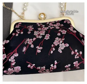 Detail of pink cherry blossom embroidery on black satin fabric with pearl clasp