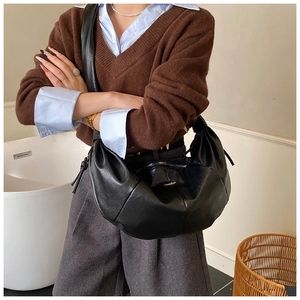 Detail shot of black crescent hobo bag in soft synthetic leather with decorative knot