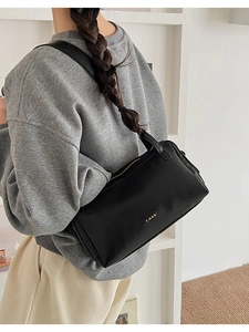 Dettaglio di una borsa a cuscino vintage nera con zip dorata e logo elegante
